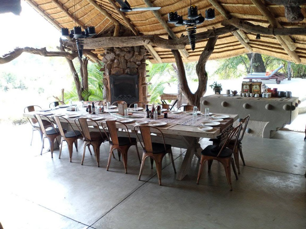 Long lodge dining table set for guests beside a stone fireplace