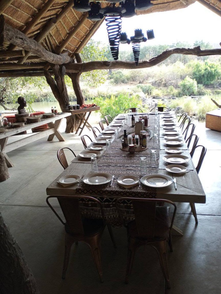Fully set dining table under lapa looking out to bush and water