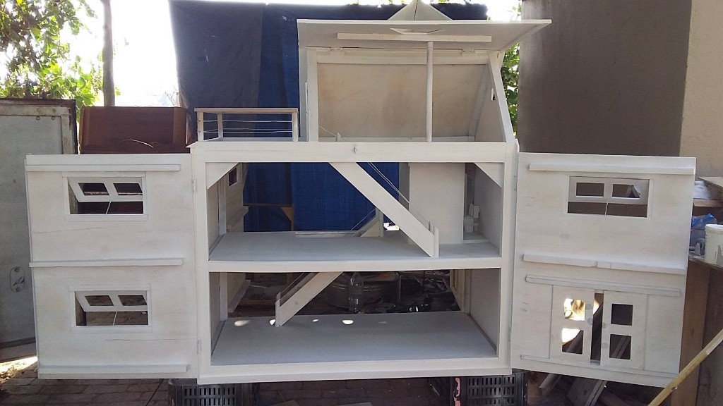 Open multi-storey wooden dollhouse on workshop crates