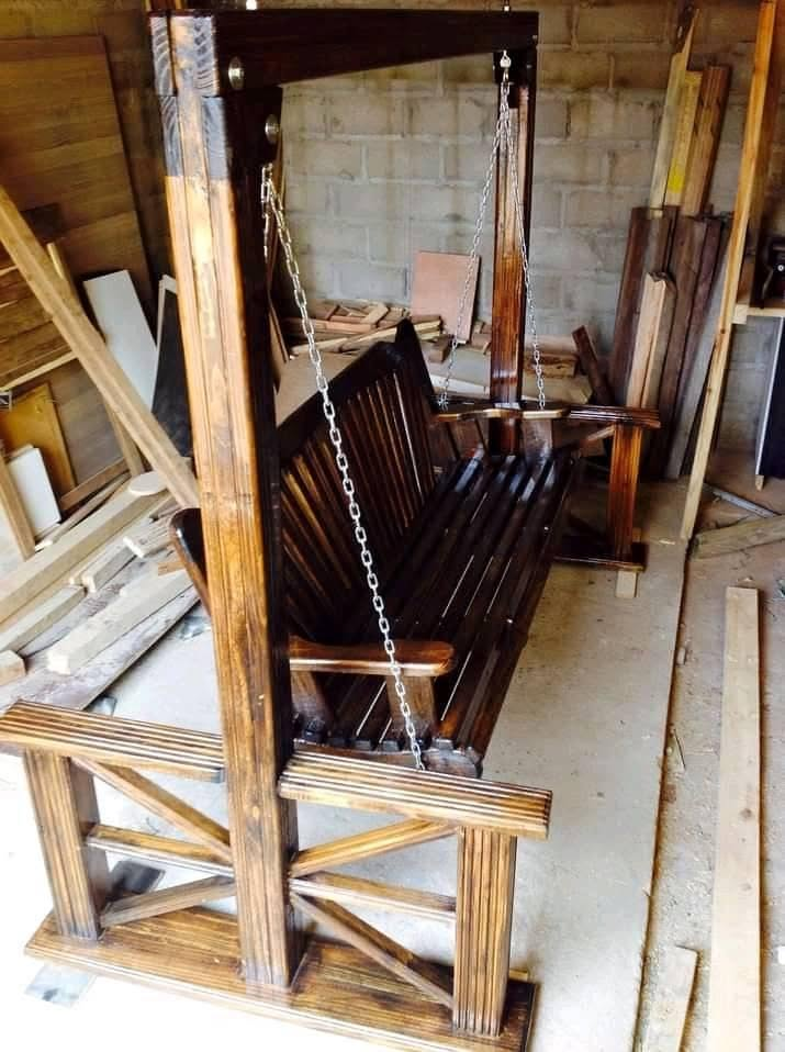 Dark stained wooden garden swing with sunburst side panels in workshop
