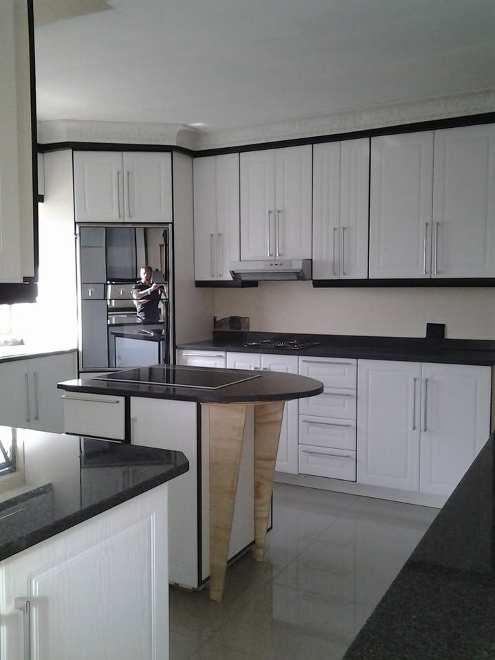 White kitchen with black counters and a timber-legged island