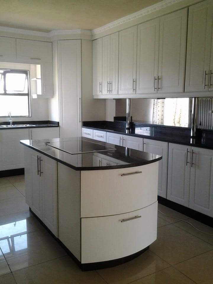 White kitchen with curved island, hob and black stone counters