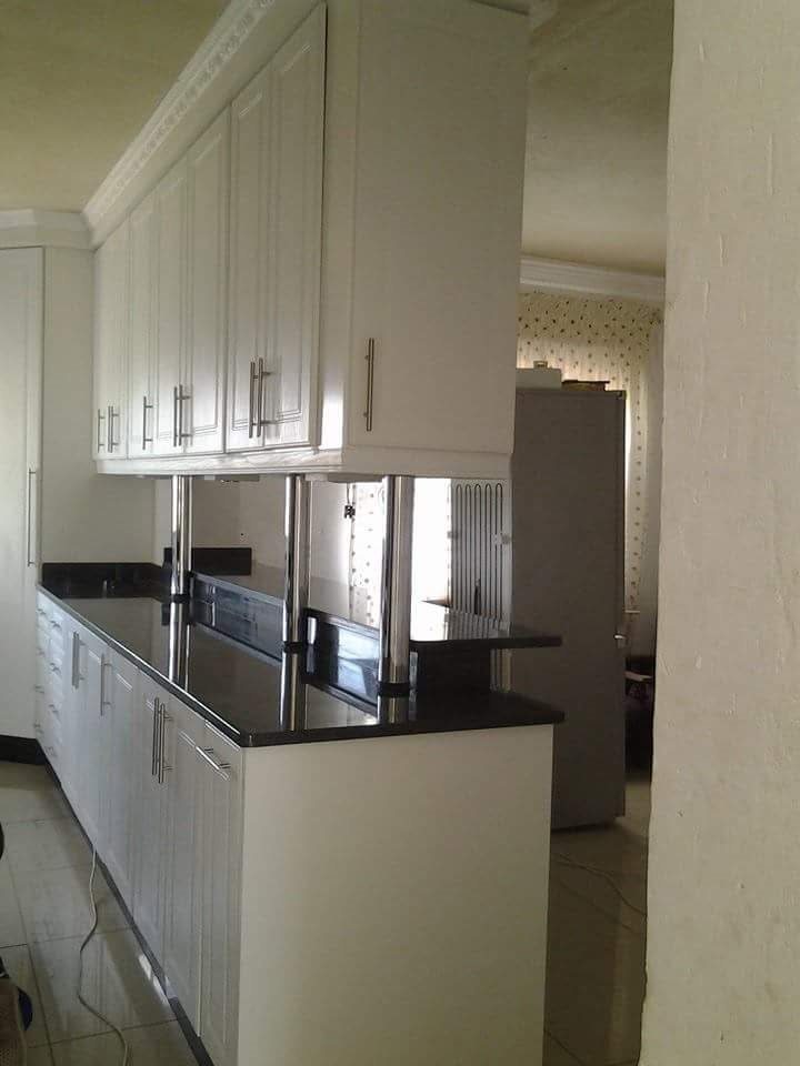 White kitchen peninsula with black stone top and chrome support posts