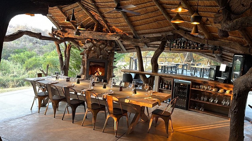 Live edge bar and dining table beside a stone fireplace