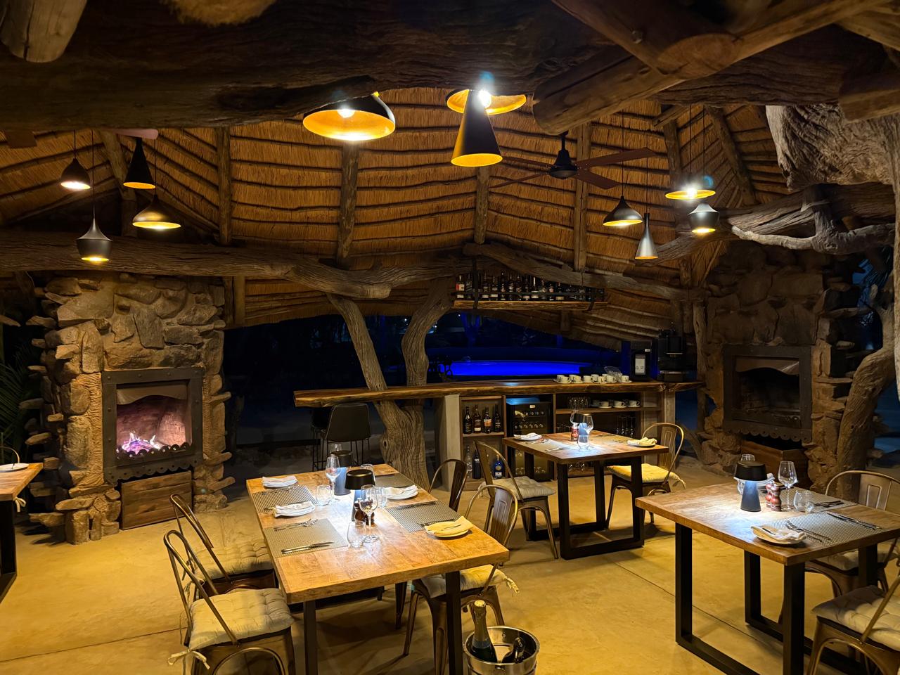 Lodge dining room at night with timber tables and stone fireplace