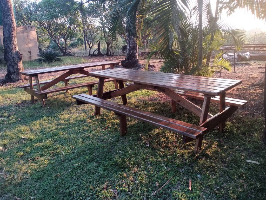 Two dark-stained wooden picnic tables on a lawn