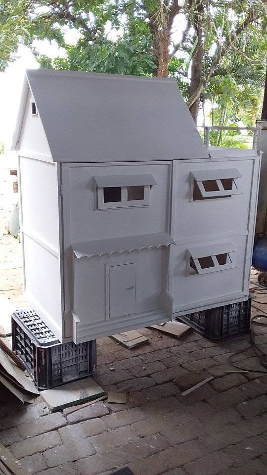 Large off-white wooden playhouse elevated on crates
