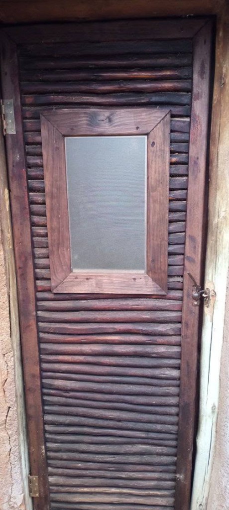 Custom dark wooden door with horizontal ribbed slats and small window