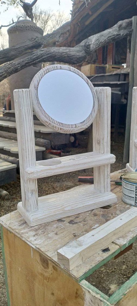 Close-up of a whitewashed wooden vanity mirror with shelf